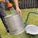 Paket: Fruktkross Manuell 9L + Stödben & Fruktpress Original 12L Rengöring av en cylinderformad presskorg med hjälp av en vattenslang utomhus på gräsmattan